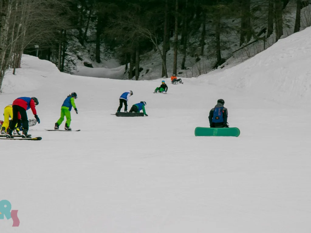 Snowboardgruppe übt am Hang, einige knien im Schnee.